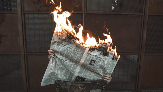 Eine Person liest eine brennende Zeitung.