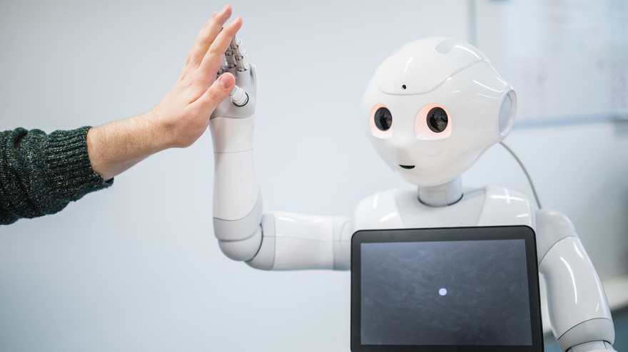 Eine Menschenhand gibt einem Roboter einen Handschlag