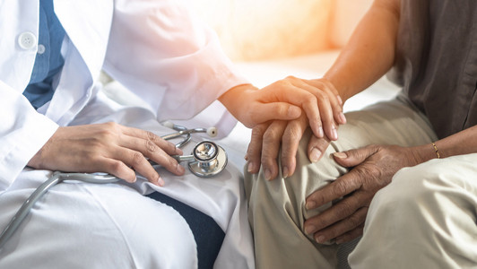 Ein Arzt legt seine Hand auf die Hand eines Patienten.