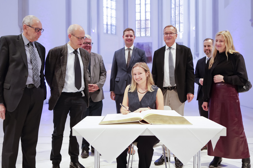 Die Rednerin Veronika Solopova (vorne Mitte) und die Redner Konrad Liessmann (l.) und Fritz Breithaupt (nicht im Bild) trungen sich ins Goldene Buch der Stadt Bamberg ein. Umringt waren sie dabei von (v.l.n.r.) Christian Illies, den Bürgermeistern Wolfgang Metzner und Jonas Glüsenkamp, dem Oberbürgermeister Andreas Starke sowie Universitätspräsident Kai Fischbach und Eva-Maria Bauch, CEO der Mediengruppe Oberfranken.