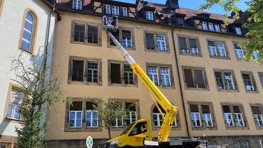 Nistkästen für Mauersegler werden mit Hilfe eines Krans an der Fassade befestigt.