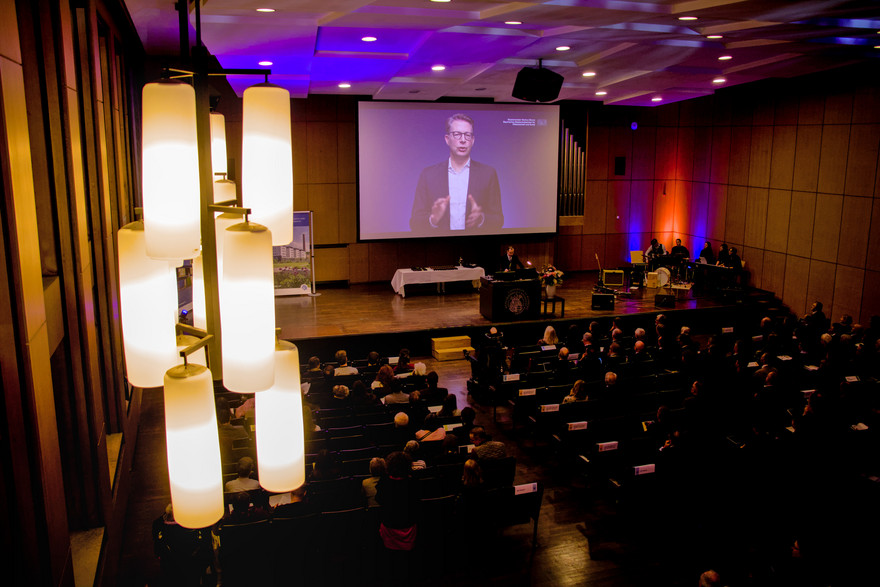 Wissenschaftsminister Markus Blume auf der Leinwand zu sehen mit einem Videogruß
