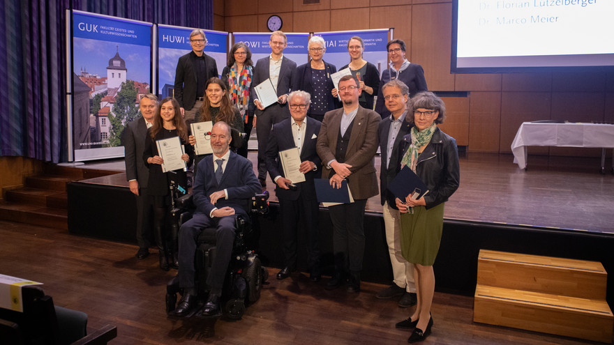 Die Forschungspreisträgerinnen und -preisträger gemeinsam mit Thomas Saalfeld vor der Bühne.