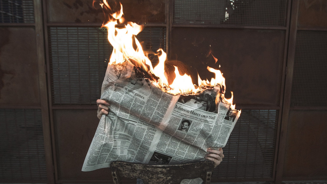 Eine Person liest eine brennende Zeitung.