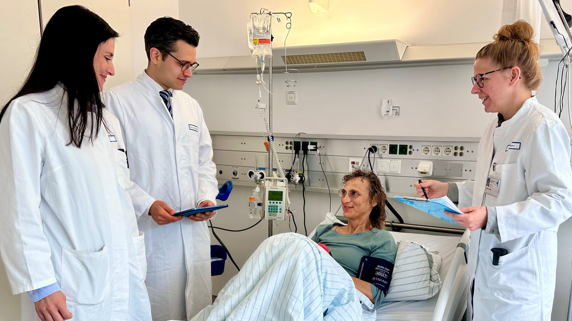 Patientin und Ärztinnen und Arzt in einem Patientenzimmer am Krankenbett.