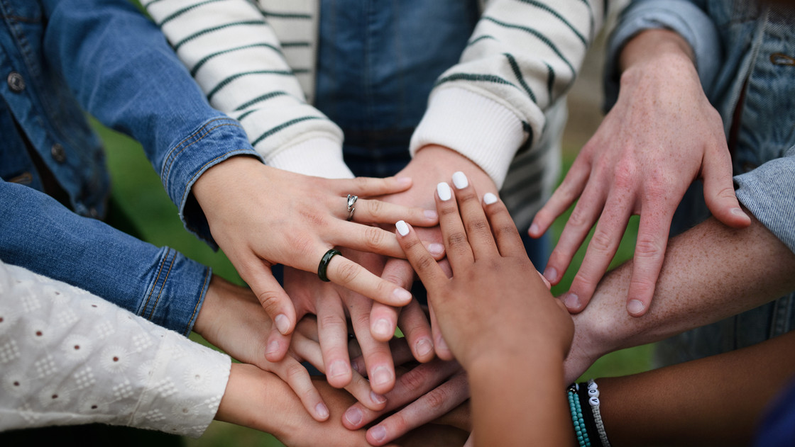 Close-up of diverse group of friends stacking their hands together in circle, Friendship and lifestyle concepts