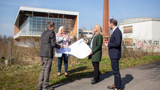 Bauamtsleiter Jürgen König zeigt der Staatsministerin Melanie Huml, der Kanzlerin der Universität Dagmar Steuer-Flieser sowie dem Universitätspräsidenten Kai Fischbach die Baupläne zum alten Hallenbad. 